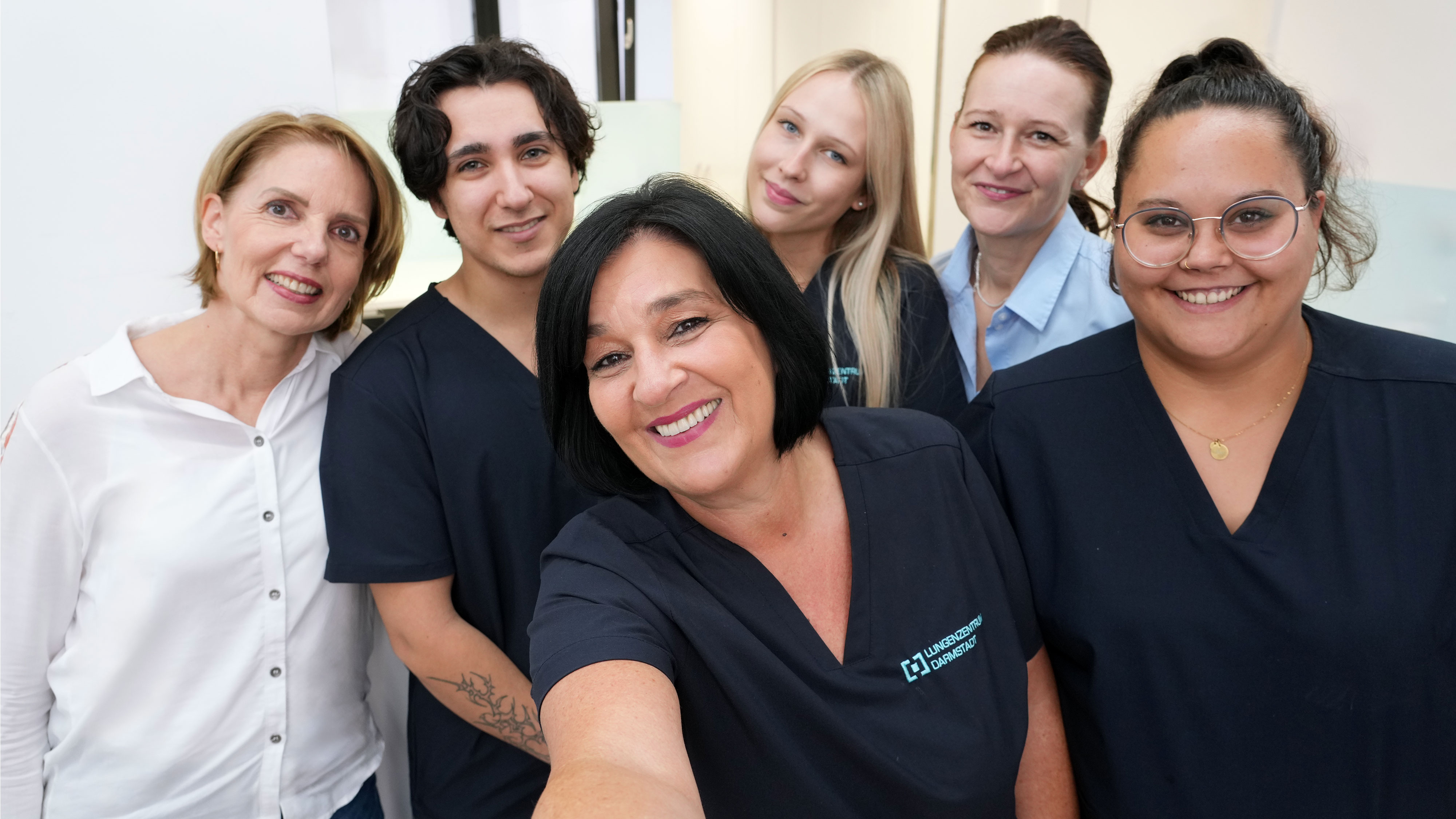 Gruppenfoto aus Selfie-Perspektive: Dr. med. Esther Bank-Weis und fünf Mitarbeitende des Lungenzentrum Darmstadt lächeln freundlich in die Kamera